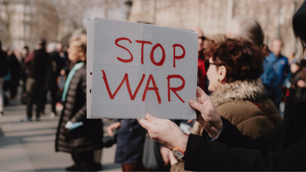 Eine Person hält ein Schild hoch auf dem "Stop War" steht